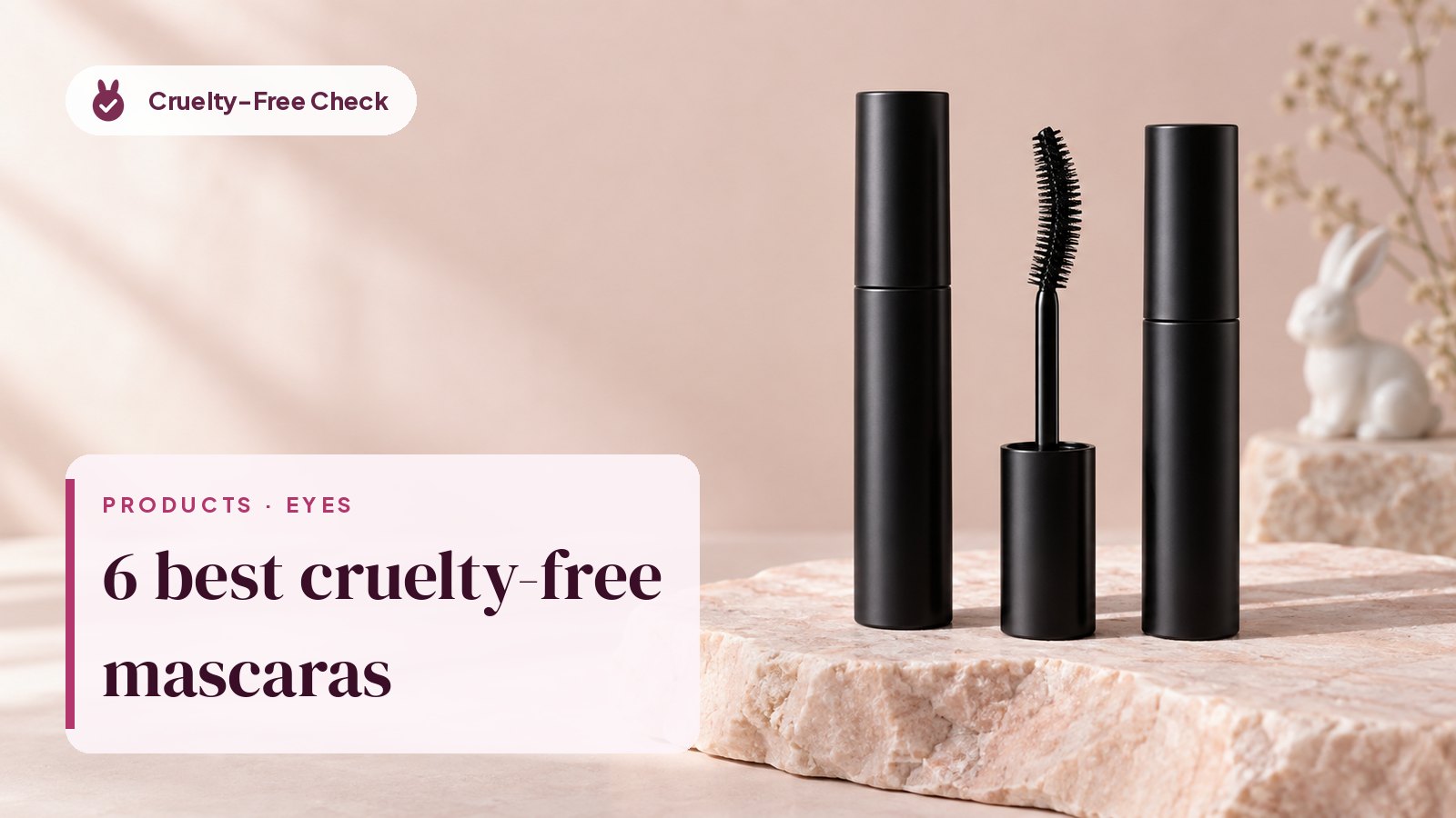 Three unbranded black mascara tubes and an open curved wand on pink stone, illustrating the best cruelty-free Mascara